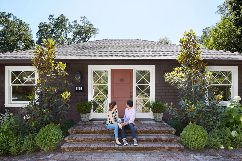 A happy couple stands in front of their new home.