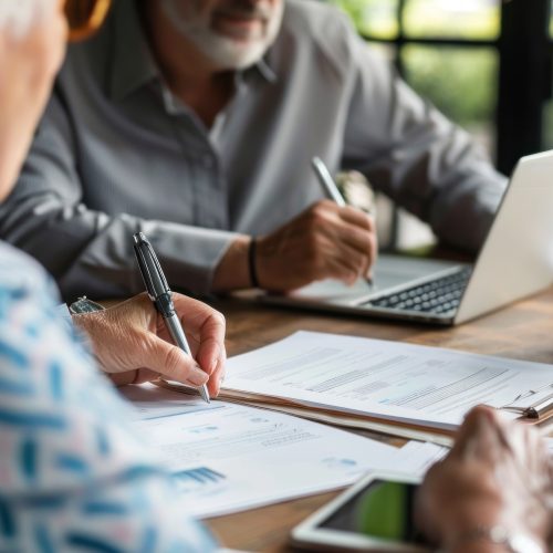 Couples in their 60s reviewing Social Security documents together at a table, discussing their retirement plans and financial options